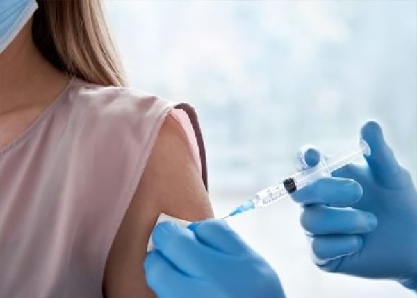 A close-up of a healthcare worker administering a vaccine to a patient wearing a mask.