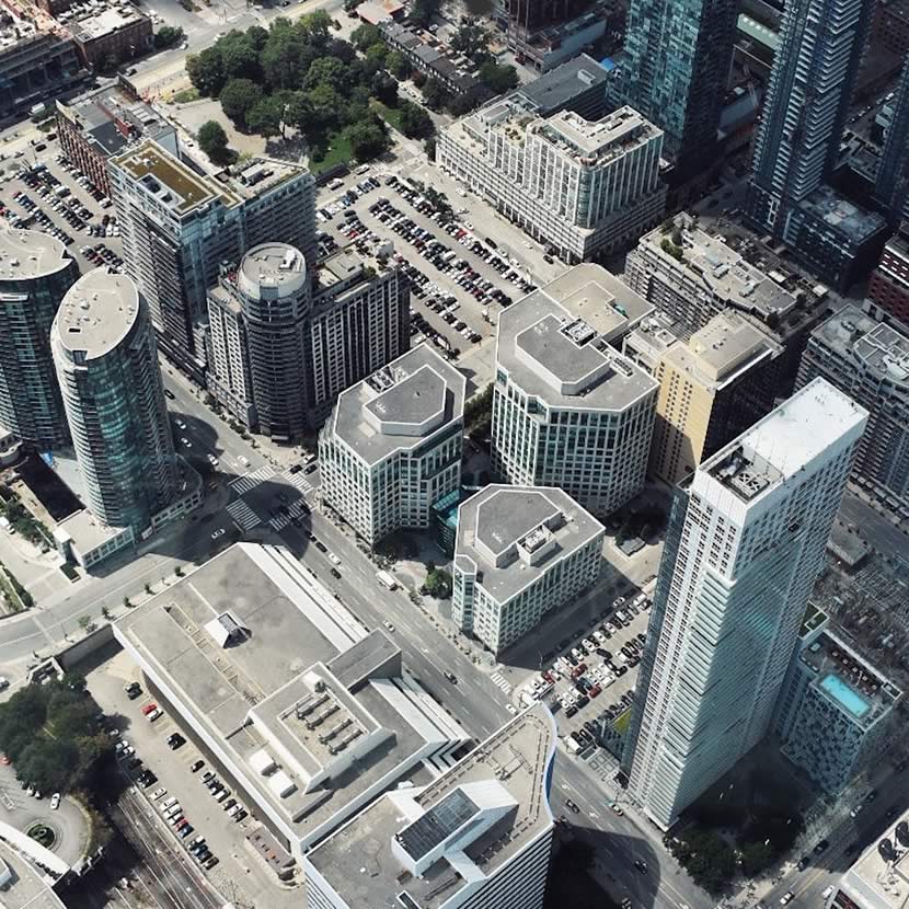 Aerial view of a cityscape featuring high-rise buildings, parking lots, and roads.