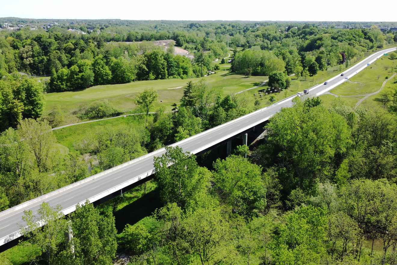 Aerial view of a highway bridge surrounded by green trees and open fields.