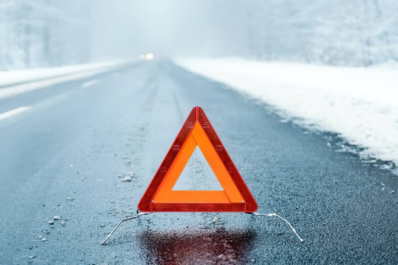 A red warning triangle positioned on a snowy road.