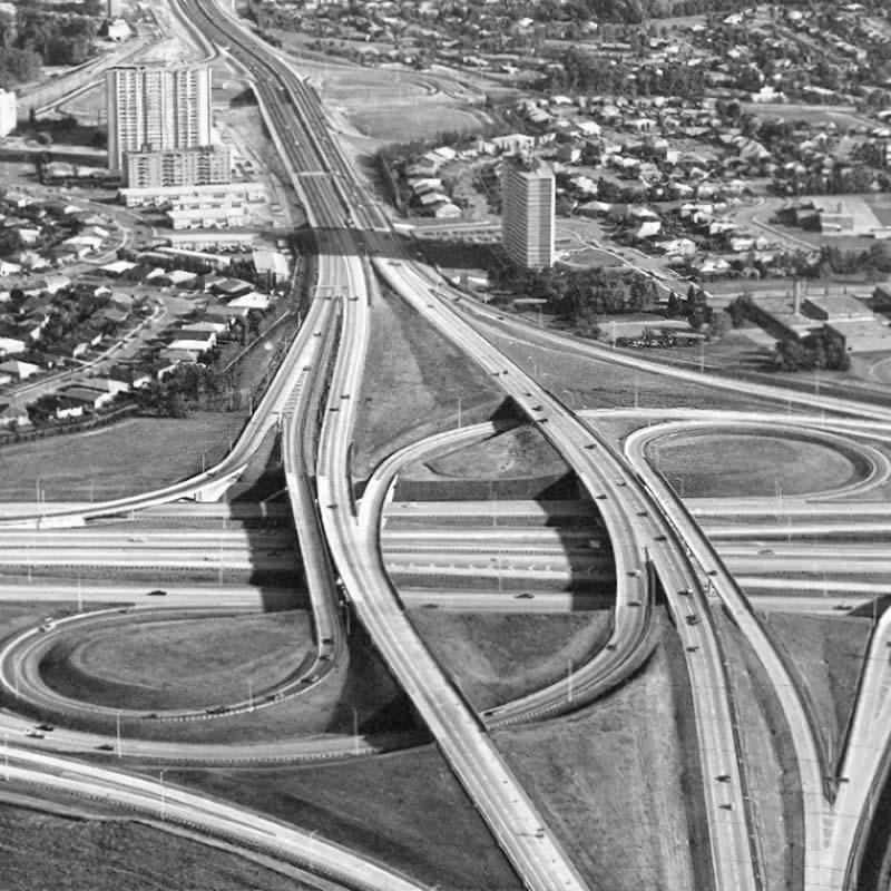 Aerial view of a complex highway interchange with multiple roadways and surrounding buildings.