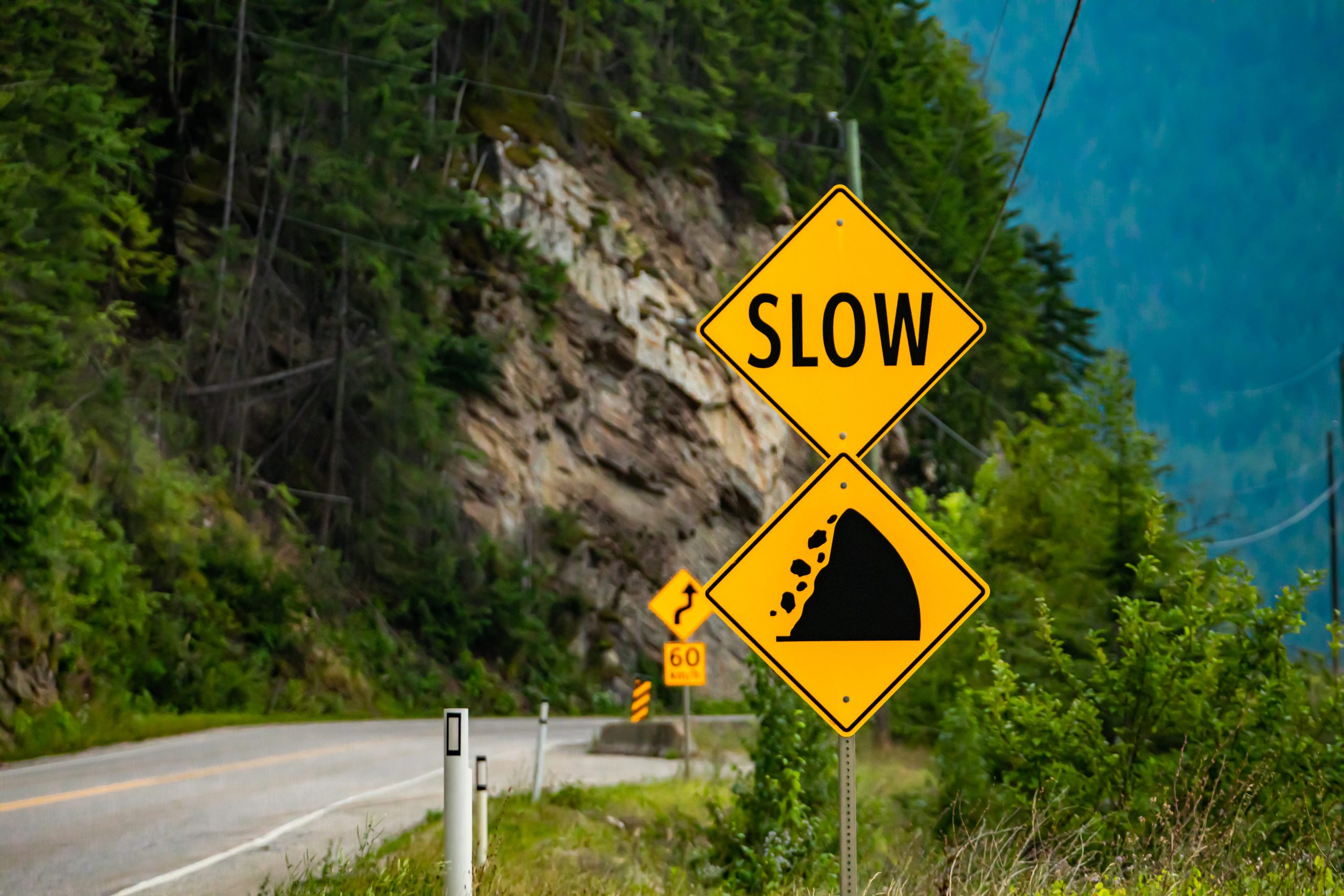 A yellow warning sign that says "SLOW" with an image depicting a slope or slide hazard.