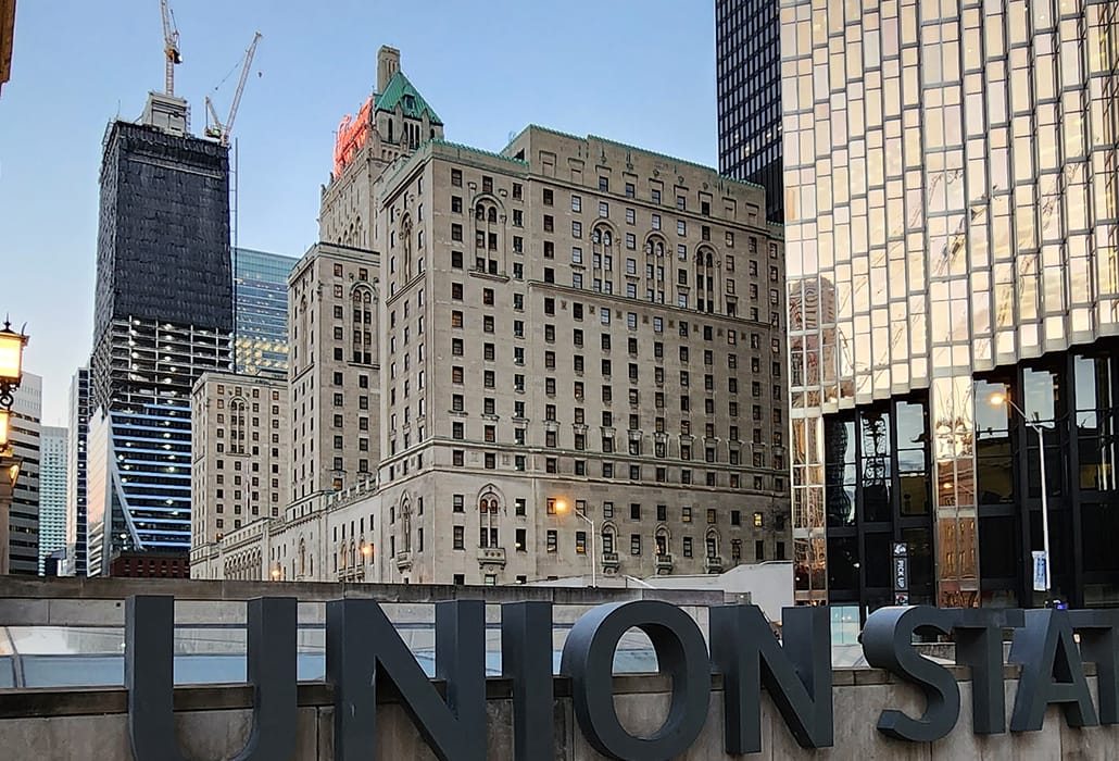 A view of Union Station with nearby buildings, including one under construction, reflecting the skyline.