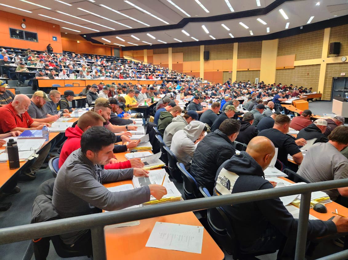 A large auditorium filled with students sitting at desks, concentrating on their work.