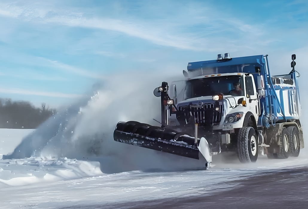 A snowplow truck clearing snow off a road.