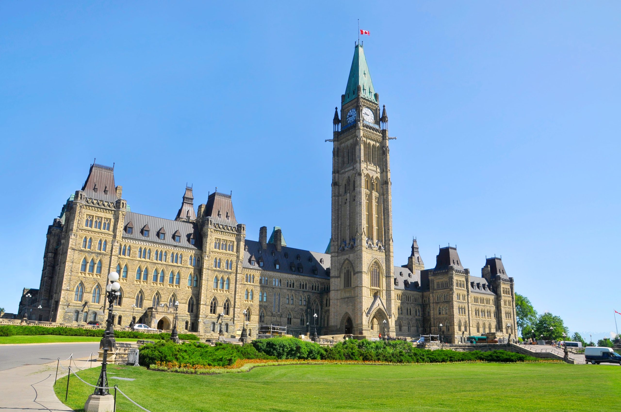 The Canadian Parliament Buildings, featuring the iconic Peace Tower, under a clear blue sky.